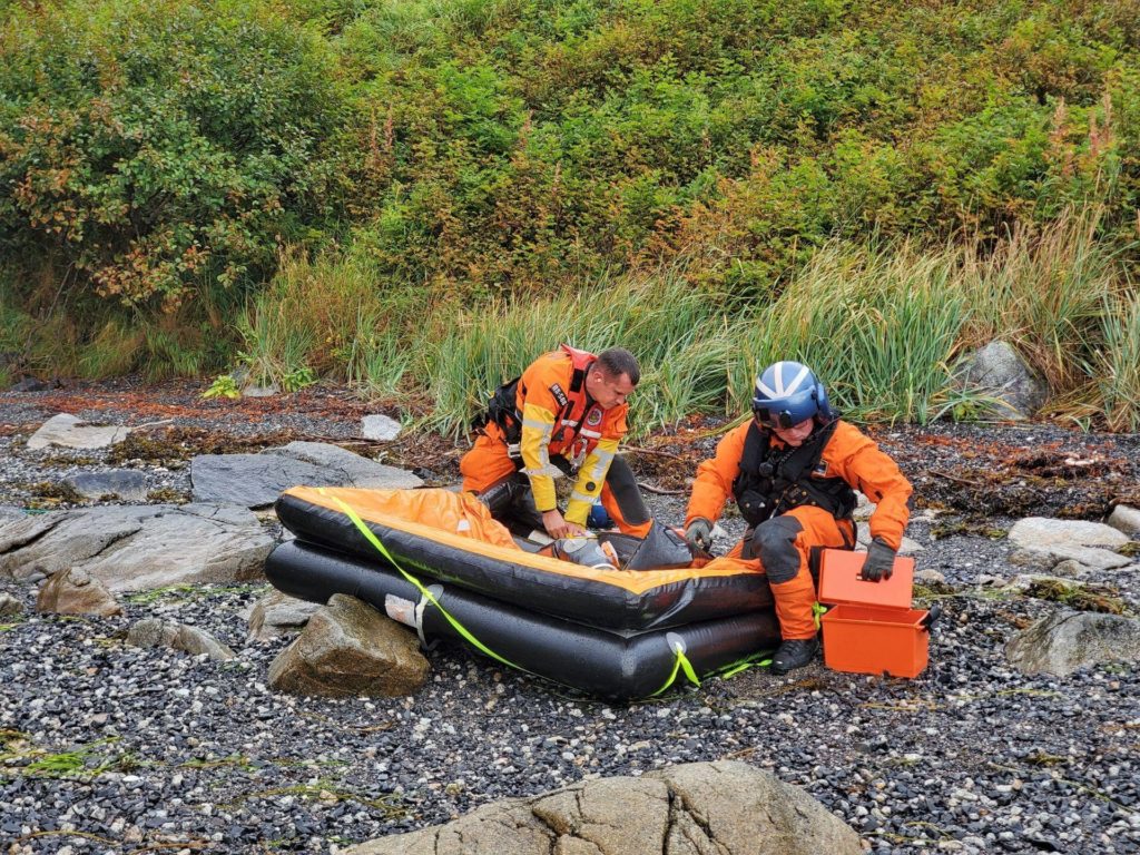 Coast Guard aircrew recover a life raft in Three Saints Bay