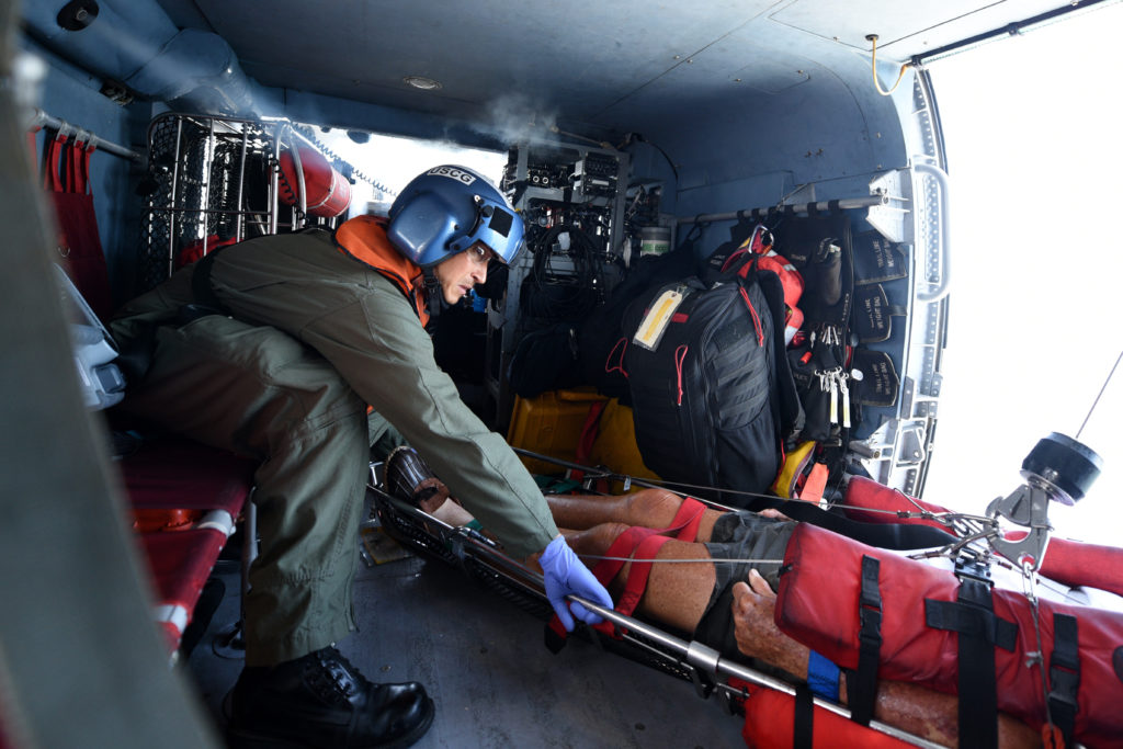 Kris Vanleeuwan (izquierda), uno de los paramédicos del Equipo de Tácticas Especiales y Rescate del Departamento de Bomberos de San Diego (STAR), ayuda a embarcar al hombre de 91 años a bordo del helicóptero MH-60 Jayhawk del Sector San Diego, USCG MEDEVAC posible ictus