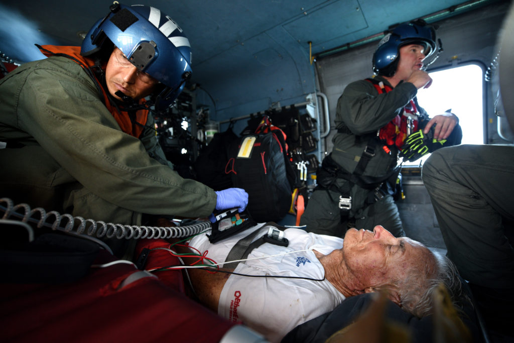  El paramédico Kris Vanleeuwan (izquierda), del Equipo de Tácticas Especiales y Rescate del Departamento de Bomberos de San Diego (STAR), asiste al hombre de 91 años a bordo del helicóptero Jayhawk, USCG MEDEVAC posible ictus
