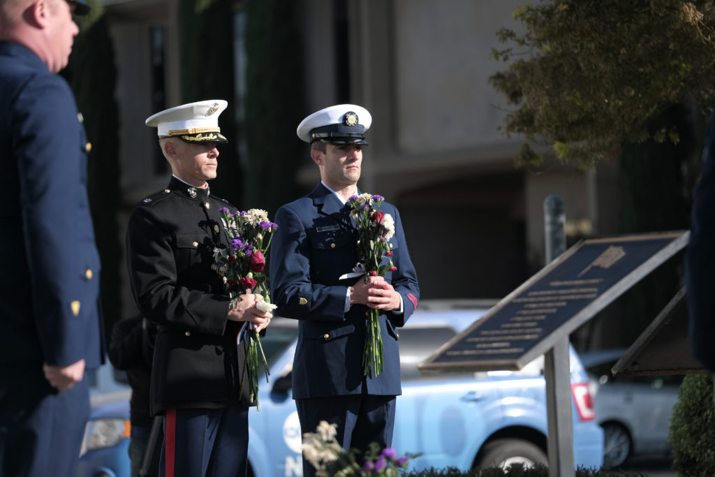 Marine Corps Lt. Col. Ryan Welborn and Coast Guard Petty Officer 2nd Class Logan Schindler hold flowers as they participate in the honor platoon during a remembrance ceremony, Oct. 29, 2019, at Coast Guard Air Station Sacramento for fallen aircrews for the 10th anniversary of an aircraft collision between a Coast Guard HC-130 Hercules aircraft and a Marine Corps AH-1 Super Cobra helicopter. 