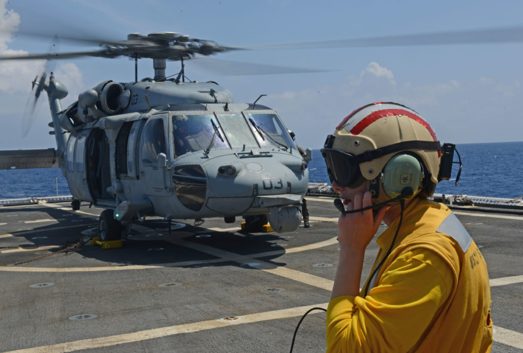 Ens. Olivia Calabro, landing signal officer aboard Coast Guard Cutter Stratton, relays communications to the pilot house after an MH-60S Seahawk helicopter crew. 