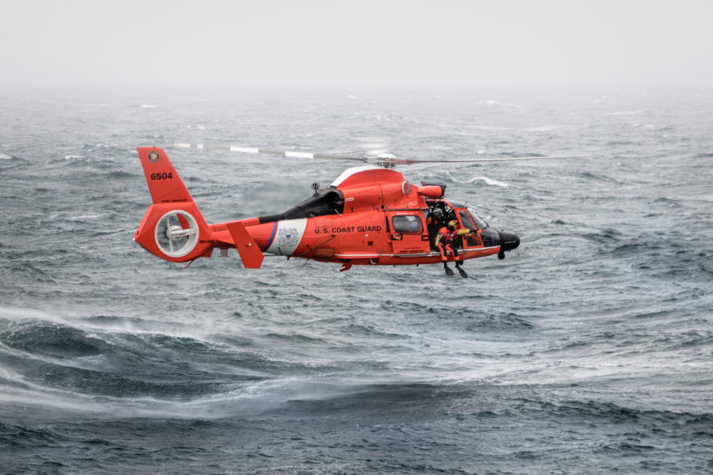 aviation survival technician deploys from an MH-65 Dolphin helicopter, from Sector Field Office Port Angeles, Coast Guard Royal Canadian Navy