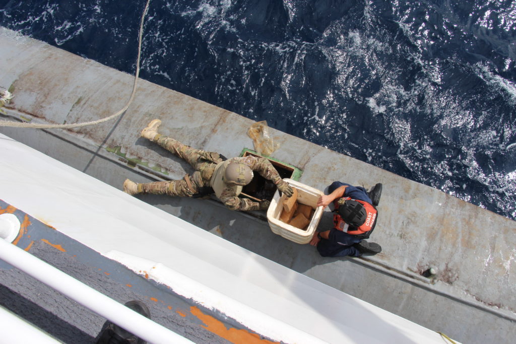 Crew members from the Coast Guard Cutter James and Tactical Law Enforcement Team-South (TACLET-South) remove contraband from a low profile vessel in the Eastern Pacific Ocean. 