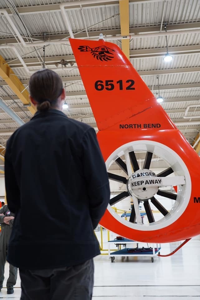 A member of the Confederated Tribes of Coos, Lower Umpqua and Siuslaw Indians, looks up at the new tail art on an MH-65 Dolphin helicopter at Coast Guard Sector North Bend in North Bend, Oregon Nov. 22, 2019. The tail art was designed to incorporate traditional tribal references in honor of the cultural heritage of the communities in which the Coast Guard members serve. 
