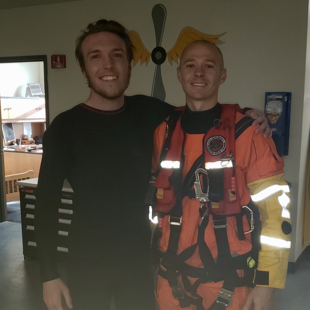 Petty Officer 2nd Class Michael Hernon, a Coast Guard Sector Humboldt Bay rescue swimmer, stands with Kris Nagel, a distressed surfer who was rescued by the Coast Guard when he was reportedly swept toward rocks near Moonstone Beach while he was surfing, Dec. 15, 2019. 