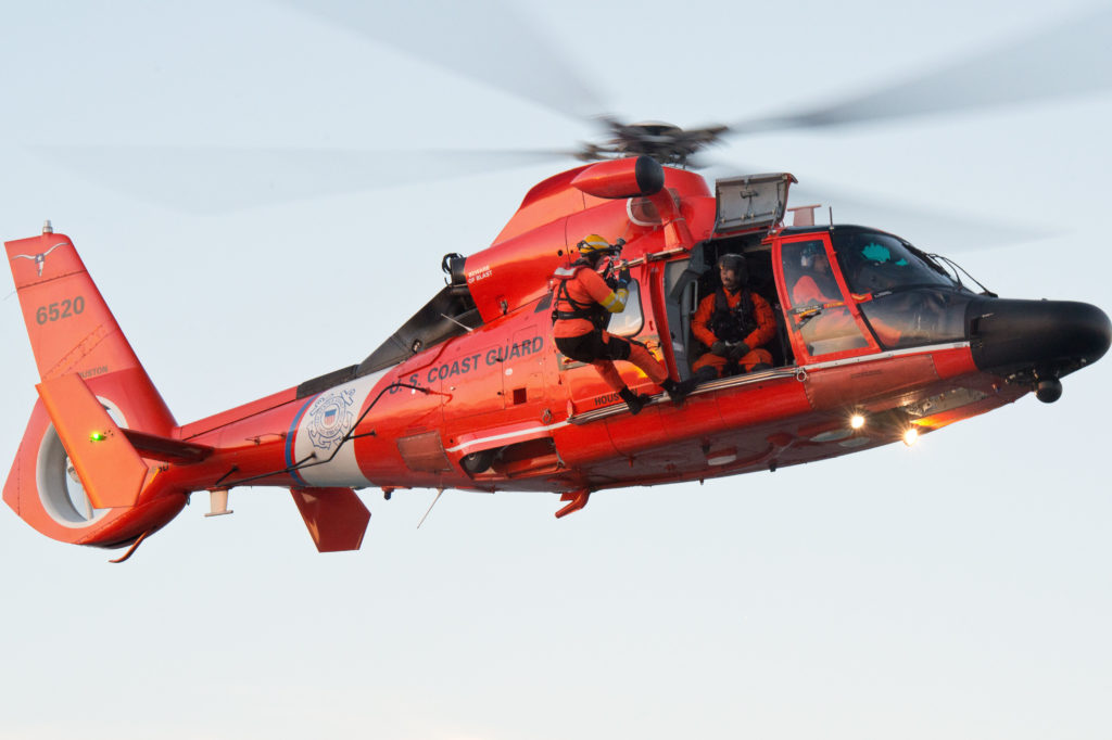 An MH-65 Dolphin rescue swimmer is lowered during air operations training off Galveston, Texas. Coast Guard vessel collision.