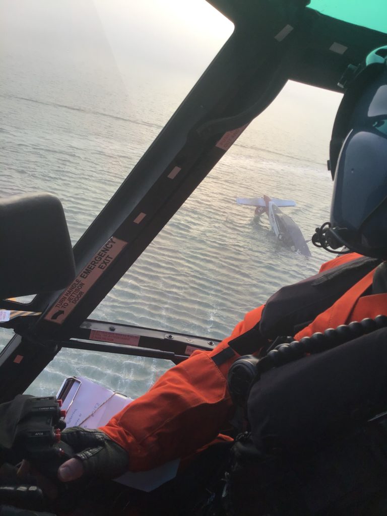 A Coast Guard MH-65 Dolphin pilot from Coast Guard Air Station San Francisco scans the site of a downed aircraft, Feb. 6, 2020, in Arcata Bay, California. The Coast Guard continues to monitor the situation and any possible environmental impacts. Plane Crash Humboldt Bay