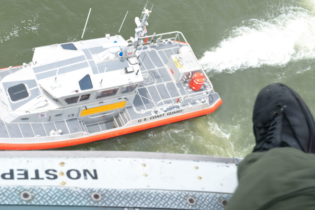 Air Station Houston MH-65 Dolphin rescue helicopter hovers over a Station Galveston 45-foot boat during a search and rescue hoist demonstration for the SAR Workgroup at Sector Field Office Galveston, Texas. 