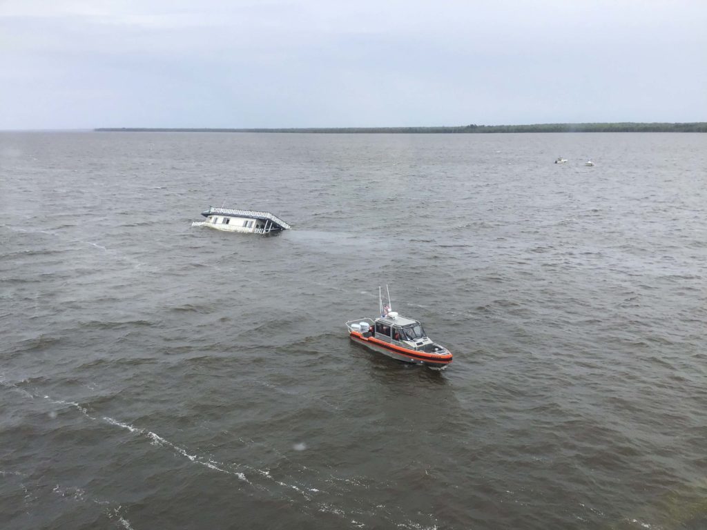 A boatcrew from Coast Guard Station Elizabeth City approach a sinking houseboat on the Scuppernong River in Albemarle Sound, June 13, 2020. Two people were hoisted from the vessel and a cat was transported to shore by the boatcrew. RBS. Response Boat-Small.