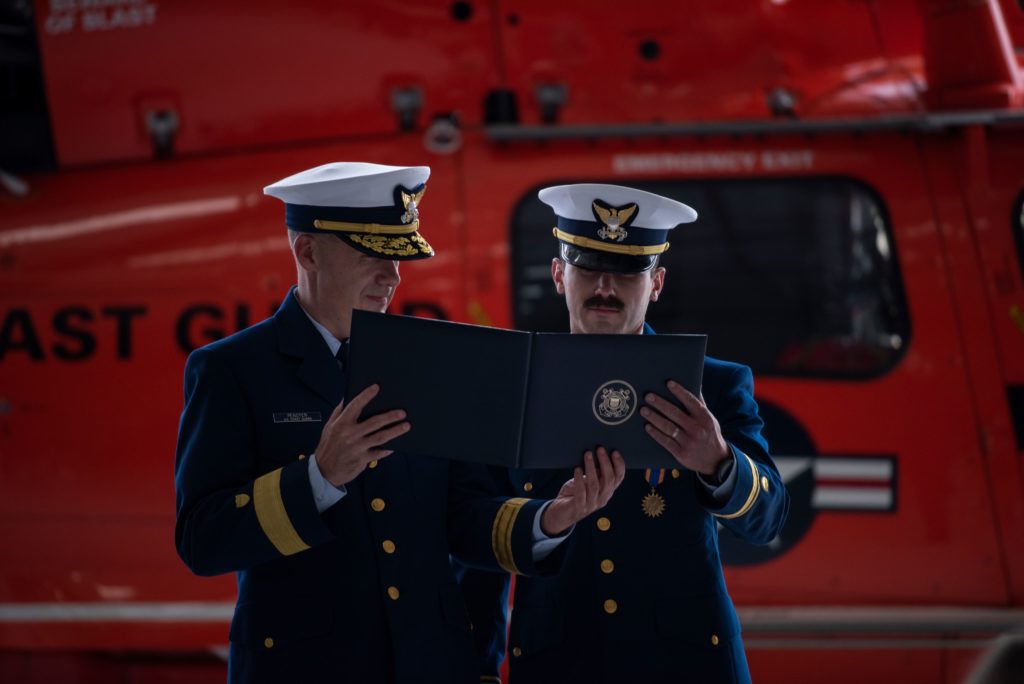 Rear Adm. Brian Penoyer, Eleventh Coast Guard District commander, presents the Air Medal to Lt.j.g. Adam Ownbey, a Coast Guard Air Station Humboldt Bay MH-65 Dolphin helicopter pilot, Aug. 6, 2020, in Humboldt Bay, California. The Air Medal is a prestigious award that is presented to an Armed Forces member who has distinguished themselves by heroic or meritorious achievement in aerial flight during the rescue of survivors.