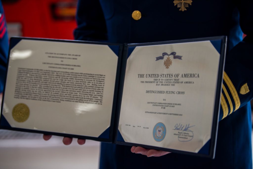 Cmdr. Derek Schramel, a pilot at Coast Guard Air Station Humboldt Bay, holds his Distinguished Flying Cross citation following an award ceremony, Aug. 6, 2020, in Humboldt Bay, California. 