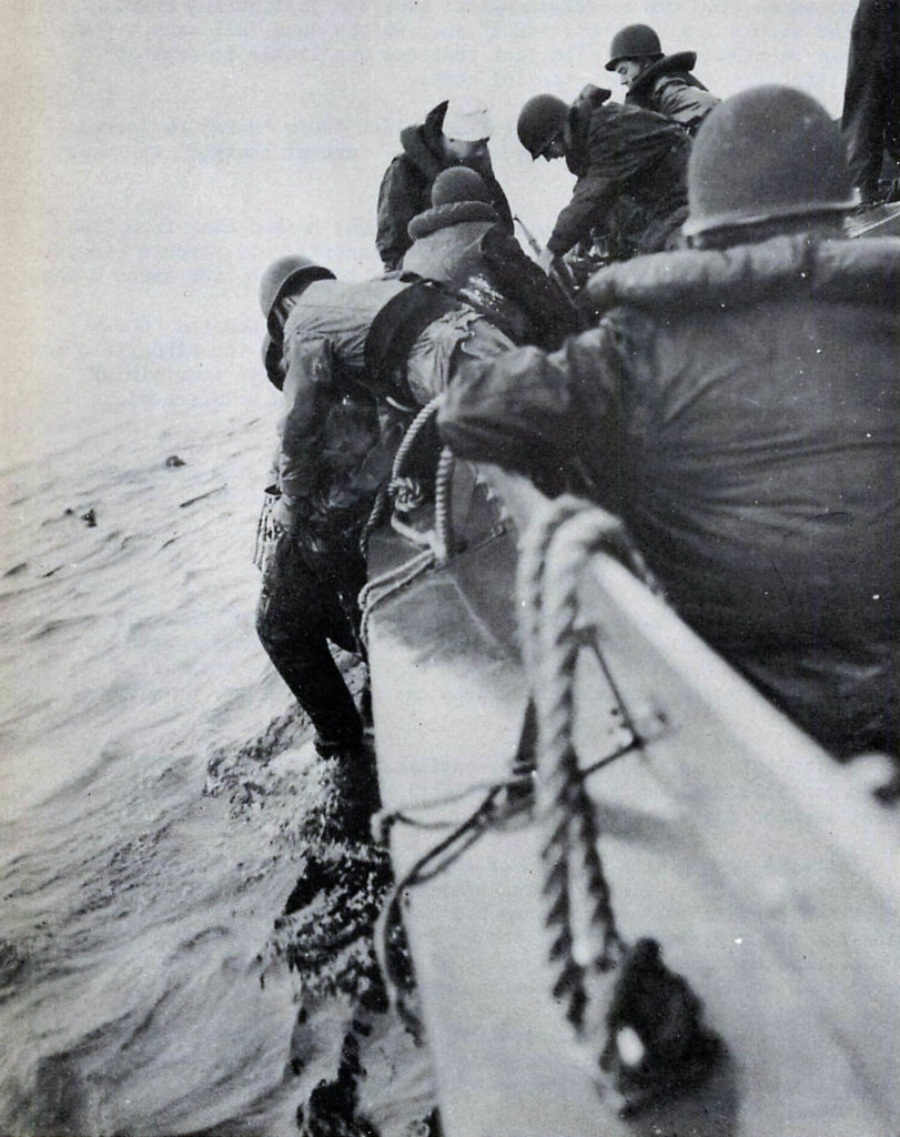 Coast Guardsmen aboard an 83-foot wooden patrol boat rescue survivors from the English Channel near Normandy, France, June 6, 1944